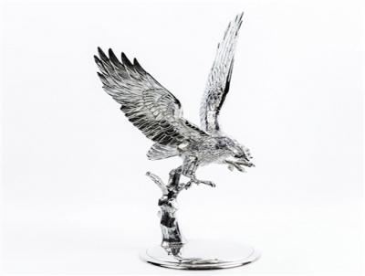 Figura realizada en plata de ley contrastada, con motivo de águila alzando el vuelo sobre una rama, en base circular.