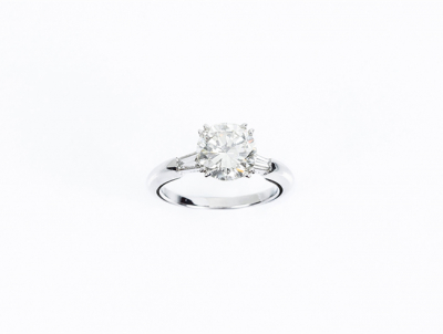 Un limpio y blanco diamante talla brillante de 2.53 ct, montado en anillo de oro blanco con diamantes trapecio en los hombros. Se acompaña de certificado del año 1987 del International Gemmological Institute (IGI, Antwerp).