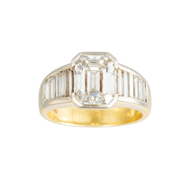 Sortija en oro bicolor con diamante central talla esmeralda custodiado por diamantes talla baguette engastados en carril.