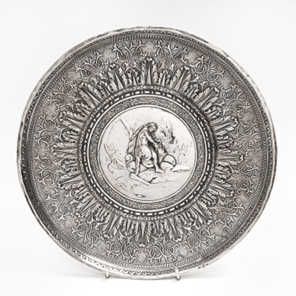 Plato de colgar en plata con medallón central representando cazador con presa y orla alrededor 