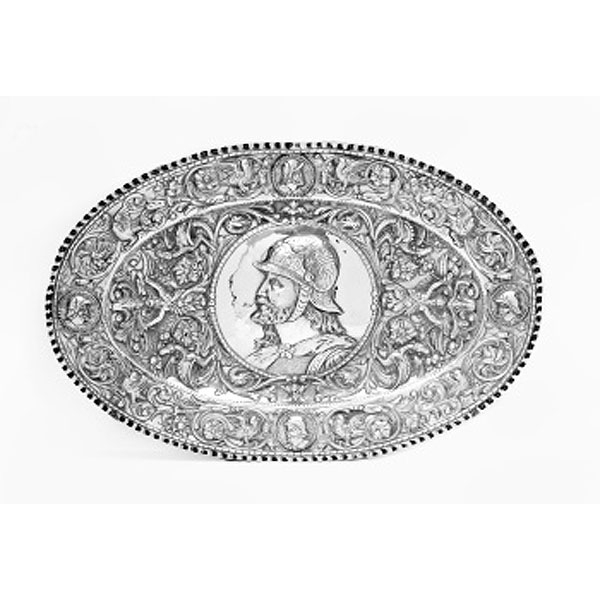 Bandeja oval en plata con medallón central representando guerrero y orla alrededor con pájaros, flores, personajes alados, animales. etc. 