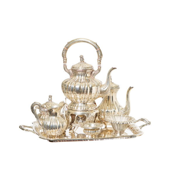 Juego de café de siete piezas en plata española punzonada con decoración gallonada, motivos de acantos y pequeñas aplicaciones en madera y símil carey, s.XX. Compuesto por bandeja, samovar, cafetera, lechera, azucarera, centrito y filtro de té.