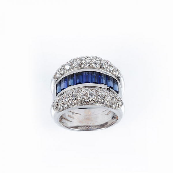 Sortija de alta joyería, en sólida montura de oro blanco 18 K, con motivo en banda central de zafiros finos azules y blancos diamantes 