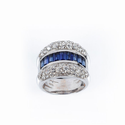 Sortija de alta joyer&iacute;a, en s&oacute;lida montura de oro blanco 18 K, con motivo en banda central de zafiros finos azules y blancos diamantes 