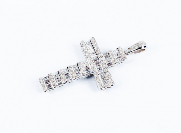 Bella cruz en oro blanco, completamente cuajada de limpios y blancos diamantes talla baguette y brillante, en bandas