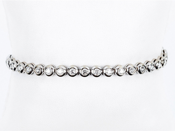 Pulsera 'rivière' en sólida montura de oro blanco con frente en fila de limpios y blancos diamantes, talla brillante, en chatón