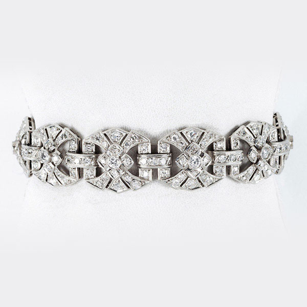 Elegante brazalete &#039;decó&#039;, años 40, en oro blanco 18 K con 10 eslabones en rosetón y bandas caladas de limpios y blancos diamantes 