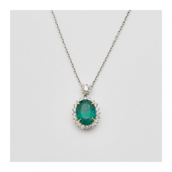 Gargantilla en oro blanco con rosetón de esmeralda de Zambia talla oval orlada por diamantes talla brillante.