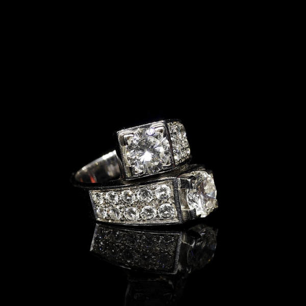 Sortija de oro blanco de 18 kt con dobles brillantes, diseño moderno de brazo plano cruzado rematado por diamante talla brillante.