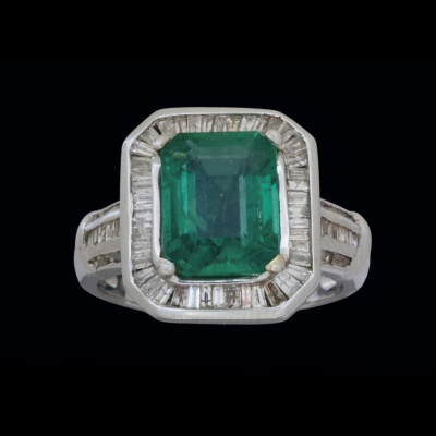 Anillo de oro blanco de 18 K. con esmeralda y diamantes calibrados.