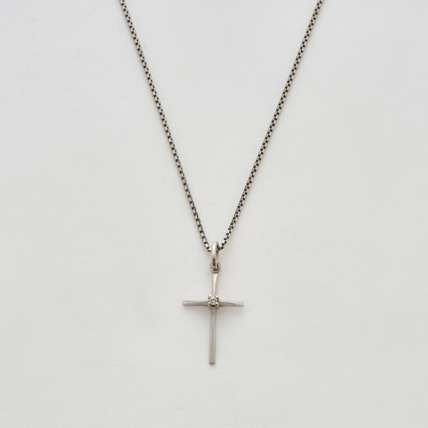 Colgante diseño cruz en oro blanco mate y brillo con un diamante talla brillante engastado en garras, 3 x 1,5 cm