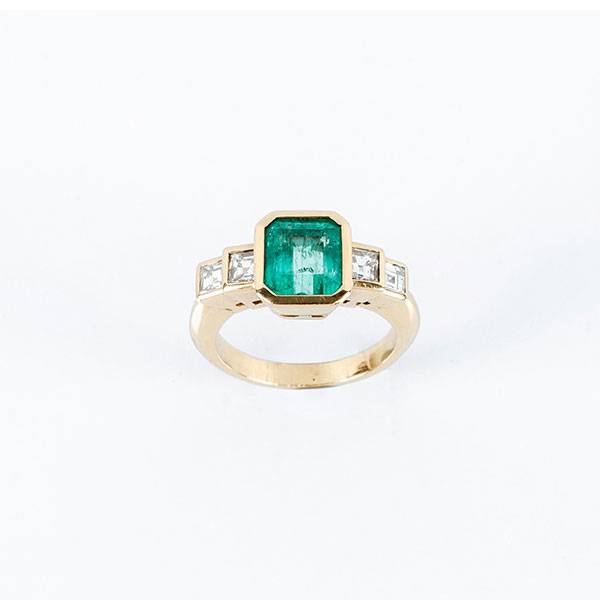 Sortija en oro amarillo 18 K con una bella esmeralda colombiana y hombros escalonados con limpios y blancos diamantes talla esmeralda 