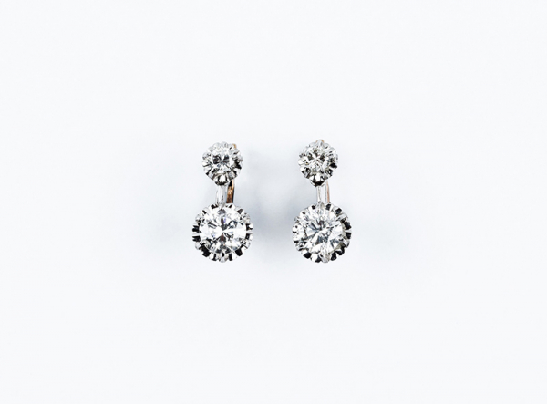 Bonitos pendientes vintage en oro blanco con un par de diamantes talla brillante en garras de ilusión, en movimiento.