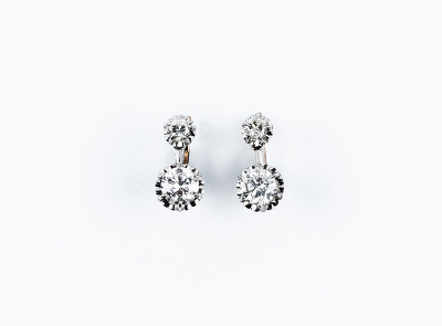 Bonitos pendientes vintage en oro blanco con un par de diamantes talla brillante en garras de ilusión, en movimiento.