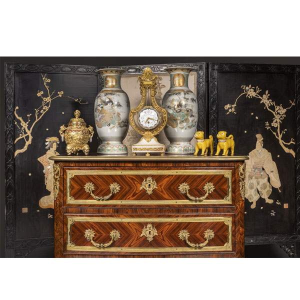 Colección de objetos decorativos orientales sobre mueble antiguo en madera con detalles de bronce dorado.