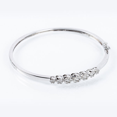 Brazalete esclavo en s&oacute;lida montura de oro blanco 18 K, con motivo central de siete rosetones de limpios y blancos diamantes naturales 