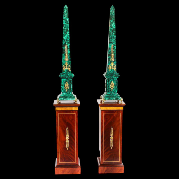 Decorativa pareja de Obeliscos relizados en Malaquita con aplicaciones en ormolu sobre peanas de caoba, siglo XX.