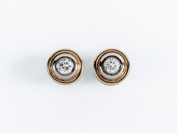 Pendientes solitario en sólida montura de oro amarillo, con un limpio y blanco diamante, talla brillante, en chatón de oro blanco