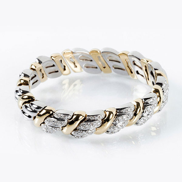 Brazalete esclavo de alta joyería en sólida montura en gallones de oro blanco y amarillo 18 K, flexible y abierto cuajadas de limpios y blancos diamantes 
