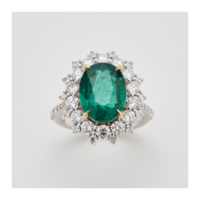 Sortija rosetón en oro blanco con esmeralda de Zambia talla oval y doble orla y brazos de diamantes talla brillante.