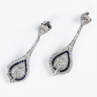 Delicados pendientes largos estilo art-decó en platino, en forma de lágrima colgante con un limpio y blanco diamante central y zafiritos azules 