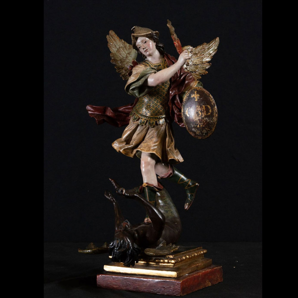 Muy importante Arcángel San Miguel sometiendo al Demonio, escuela Colonial de Quito del siglo XVIII.    En madera tallada, dorada, policromada y esgrafiada, buen estado de conservación, con emblema “¿Quién Cómo Dios?” grabado en iniciales en su escudo.
