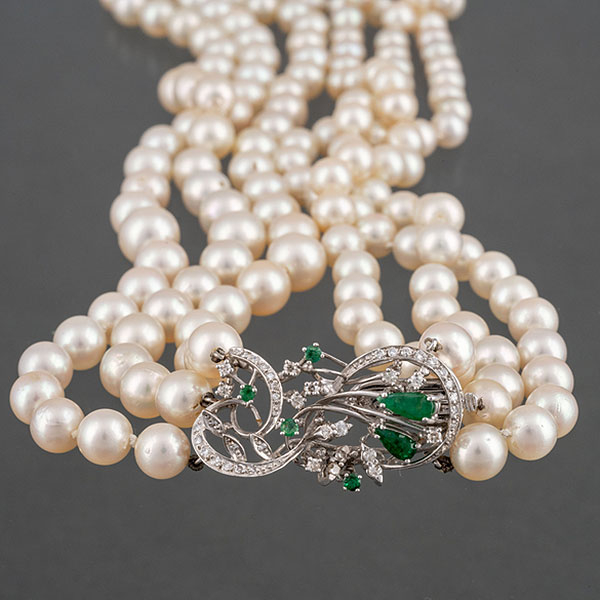Collar de perlas de tres hilos con broche en oro blanco de 18kt con brillantes y esmeraldas.