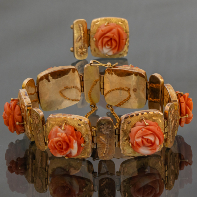 Pulsera articulada en oro amarillo de 18kt con elementos florales tallados en coral rojo.