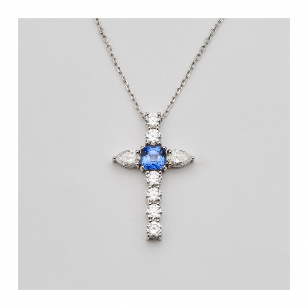 Cadena con colgante diseño cruz en oro blanco, zafiro azul talla cojín y diamantes tallas brillante y perilla.