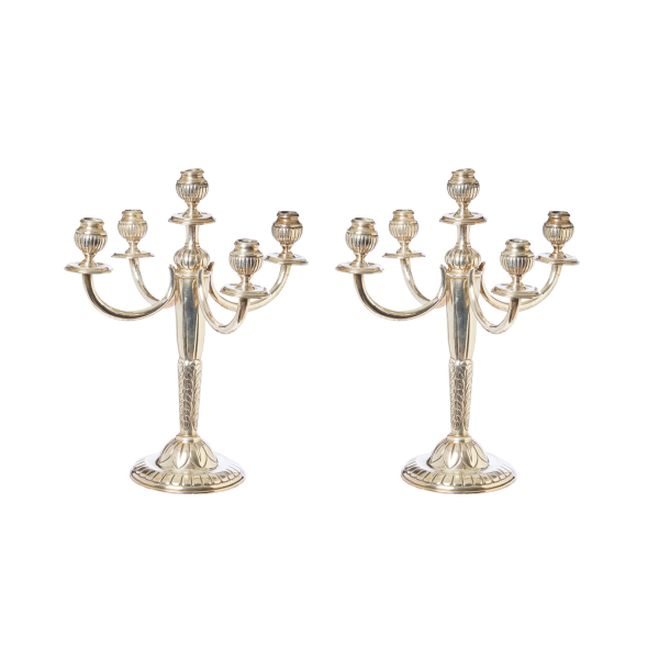 Pareja de candelabros de cinco luces en plata con decoración gallonada y motivos vegetales cincelados, fles. del s.XX.