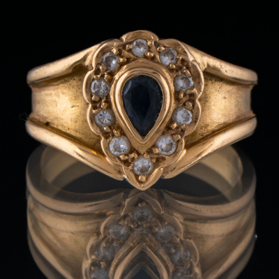 Anillo en oro amarillo de 18 kt con zafiro central talla pera orlado de brillantes.