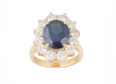 Sortija con zafiro oval de 6,33 ct. orlado de brillantes engastados en garras.   En montura de oro amarillo de 18K.