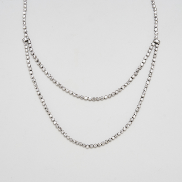 Gargantilla tipo rivière en oro blanco con dos tiras centrales de diamantes talla brillante engastados en chatón y unidas por motivos de diamantes talla baguette.