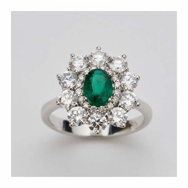 Sortija rosetón en oro blanco con esmeralda colombiana talla oval y doble orla de diamantes talla brillante.