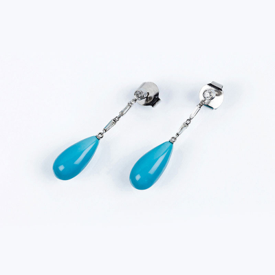 Pendientes largos en oro blanco con un diamante talla brillante en chatón y cascada articulada de limpios y blancos diamantes trapecio, con final de turquesina en perilla.