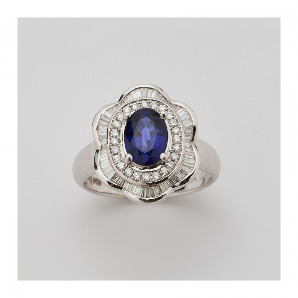 Sortija rosetón en oro blanco con zafiro azul talla oval orlado por diamantes talla brillante y bailarina de diamantes talla trapecio engastados en barras.