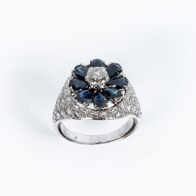 Sortija vintage de alta joyer&iacute;a en oro blanco 18 K, con un diamante natural central, talla brillante, sobre motivo en roset&oacute;n de zafiros finos azules 