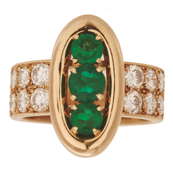 Sortija en oro con tres esmeraldas talla redonda engastadas en garras y brazos de diamantes talla brillante.