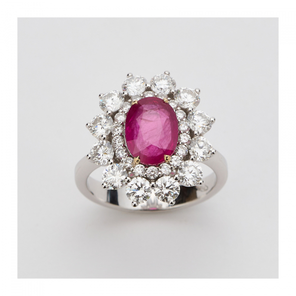 Sortija rosetón en oro blanco con rubí central talla oval y doble orla de diamantes talla brillante.
