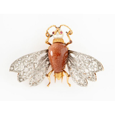 Broche representando mosca en oro amarillo y alas en oro blanco con cuerpo en piedra venturina, perla cultivada representando cabeza, y rubís en los ojos, alas con decoración de flores con 2 diamantes talla brillante y cuajado de diamantes.
