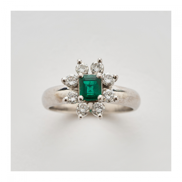 Sortija rosetón en oro blanco con esmeralda talla octogonal orlada por diamantes talla brillante.