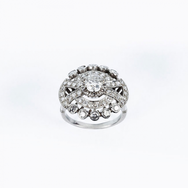 Bella sortija vintage en platino, formando un rosetón con diamante natural central, talla brillante, en garras de ilusión 