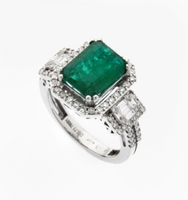 Sortija en oro blanco con esmeralda central, y orla de diamantes talla brillante y talla baguette en el brazo