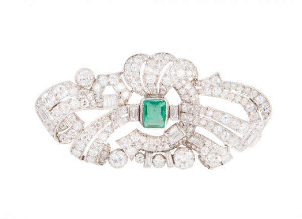 Broche de brillantes y diamantes talla baguette con diseño de cintas entrelazadas y esmeralda central.   En oro blanco de 18 K.