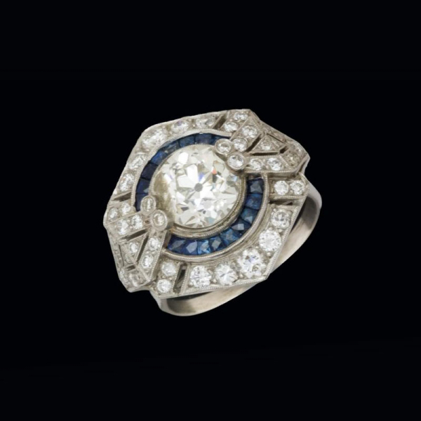 Anillo de platino con diamante central en chatón de 2,70 cts. orlado por diamantes y zafiros azules calibrados.