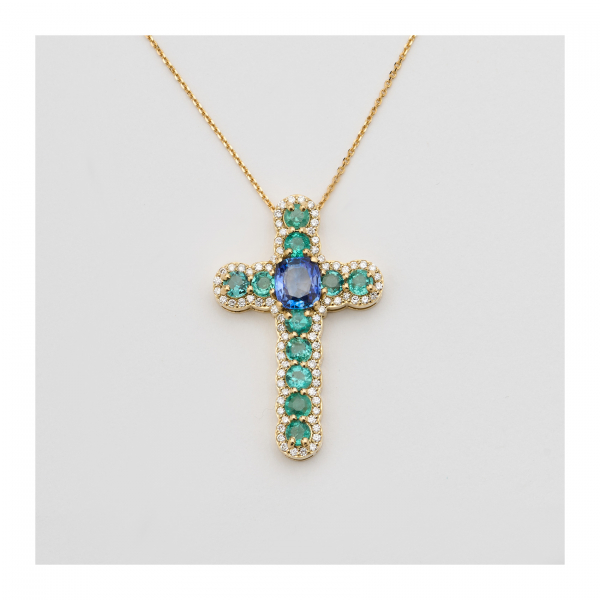 Cadena con colgante diseño cruz en oro, diamantes talla brillante, esmeraldas talla redonda y zafiro azul talla cojín engastados en garras.