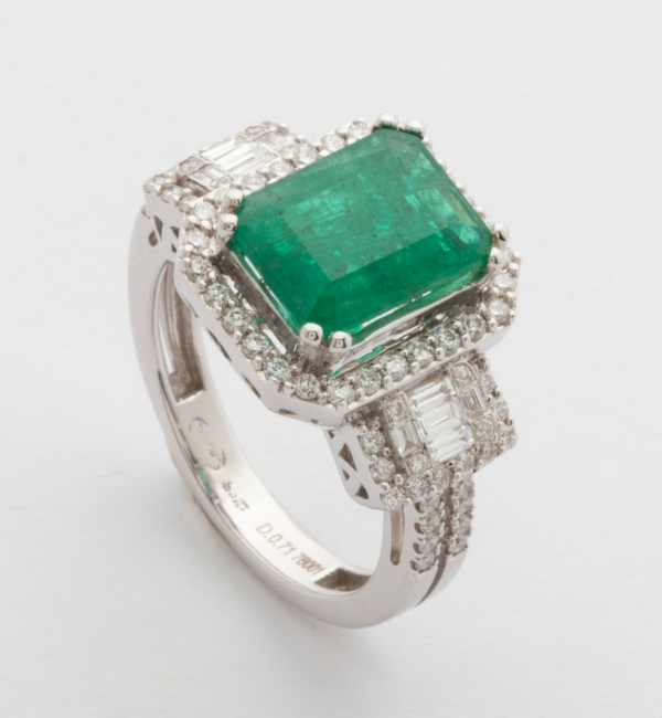 Sortija en oro blanco con esmeralda central, orla de diamantes talla brillante