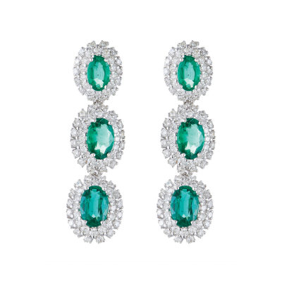 Pendientes largos en oro blanco formados por tres rosetones con esmeralda central talla oval y doble orla de diamantes talla brillante.