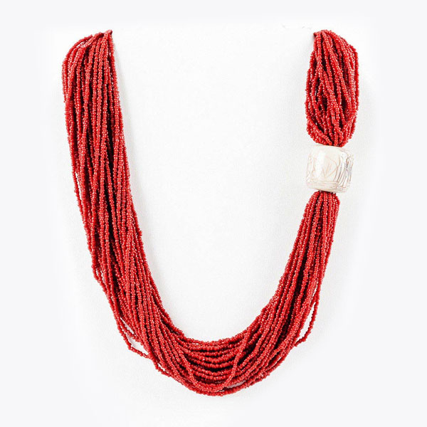 Collar largo formado por 39 hilos de pequeñas cuentas de coral rojo, con detalle de tambor tallado en hueso.