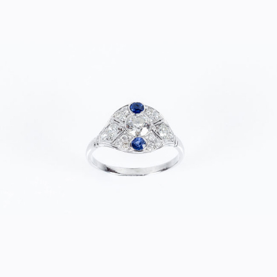 Bella sortija 'art-dec&oacute;' en oro blanco con un limpio y blanco diamante y dos zafiros azules 